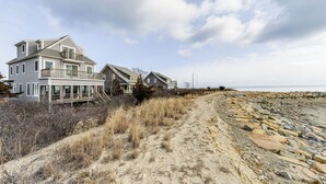 Ein Strandgrundstück mit einem Hauptgebäude und einem Nebengebäude, verbunden durch einen Sandweg zum Strand.