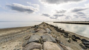 Eine felsige Küste mit einem Steg, der sich in ruhiges Wasser unter bewölktem Himmel erstreckt.