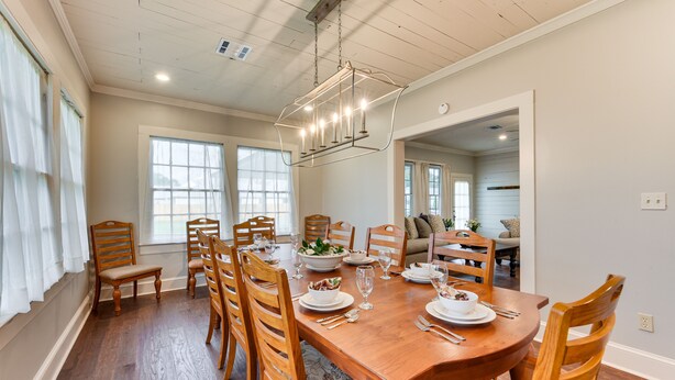 A dining room with a wooden table set for six, surrounded by wooden chairs. - Historical 1835 Home in Grand Coteau! (Grand Coteau)