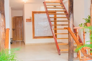 A wooden staircase with a handrail, a wooden door, and a window with a white curtain.