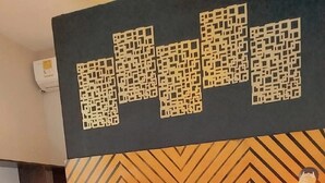 Une chambre moderne avec une tête de lit à motifs géométriques, un grand lit recouvert d’un plaid tricoté foncé et un tapis à motifs sur le sol.
