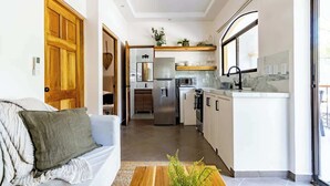 Een moderne keuken met een centraal eiland, inbouwapparatuur en een groot raam.
