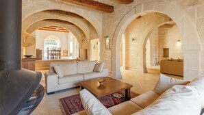 A spacious living area with stone arches, a fireplace, and a cozy seating arrangement. - Onefifty Gozitan Villa and Pool (Xaghra)