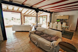 Relax in this open-plan living space with a sofa, dining table, and shelving unit.