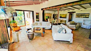 A spacious living area with a white sofa set, a coffee table, and a dining table with chairs. There is a large window providing natural light and a view of the outdoors. - Finca La Coma - modern, well-equipped villa with private pool in Benissa (Benissa)