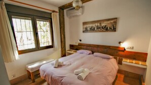 A bedroom with a large bed, a bench, a nightstand, and a cityscape painting on the wall. - Finca La Coma - modern, well-equipped villa with private pool in Benissa (Benissa)
