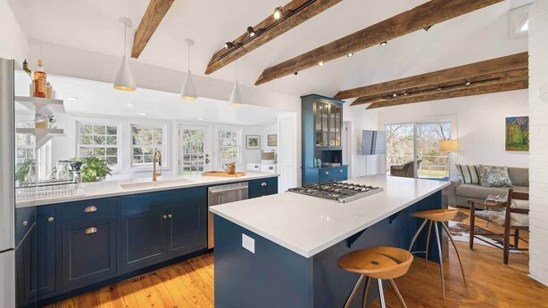 A modern kitchen with a large island, wooden beams, and bar stools. - Entire Cottage on Equestrian Farm with Zebras (Charlottesville)