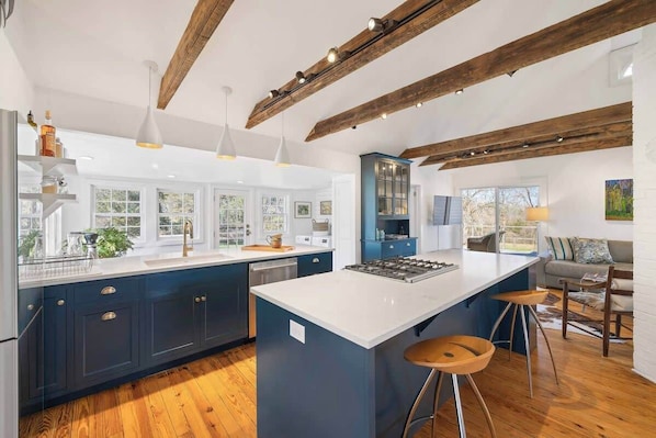 A modern kitchen with a large island, wooden beams, and bar stools.