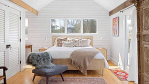 A bedroom with a bed, a chair, a window, and a door. - Entire Cottage on Equestrian Farm with Zebras (Charlottesville)