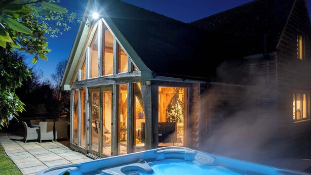 Ein Whirlpool vor einem Haus, dessen Glasfassade einen Weihnachtsbaum im Inneren zeigt.