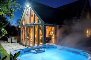 Ein Whirlpool vor einem Haus, dessen Glasfassade einen Weihnachtsbaum im Inneren zeigt.