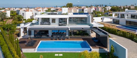 Un moderno edificio residenziale a più piani con piscina sul tetto, immerso nel verde e con vista libera sul mare.