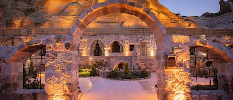 A historic stone building with an arched entrance, a central courtyard, and a well-lit facade.