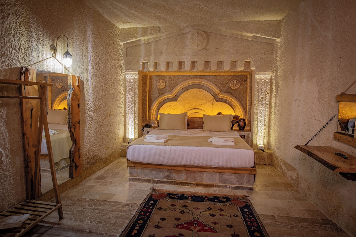 Une chambre avec un grand lit, une échelle en bois et un tapis à motifs.