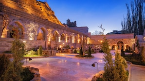 A courtyard with stone walls, arched doorways, and a central fountain. - Sur Cave Hotel (Ürgüp)