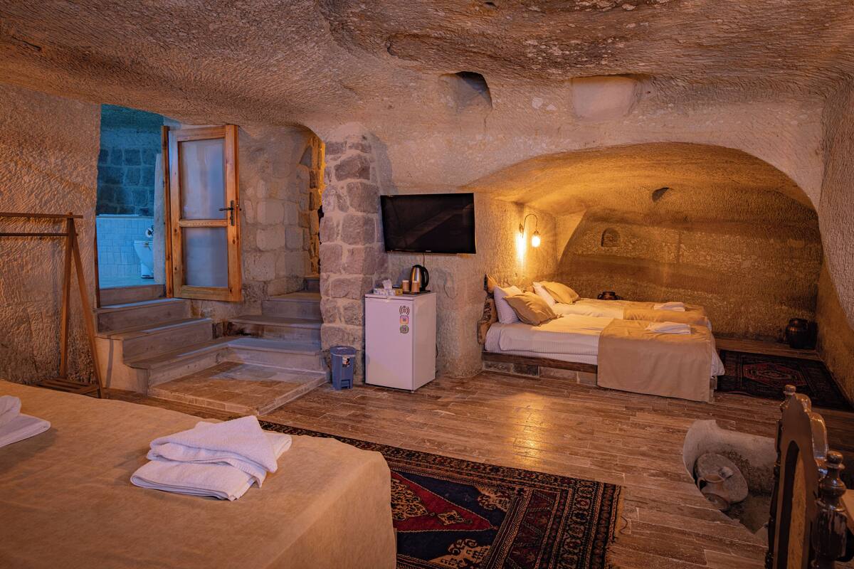 Une chambre rustique en pierre, équipée d’un lit, d’une télévision et d’un petit réfrigérateur.