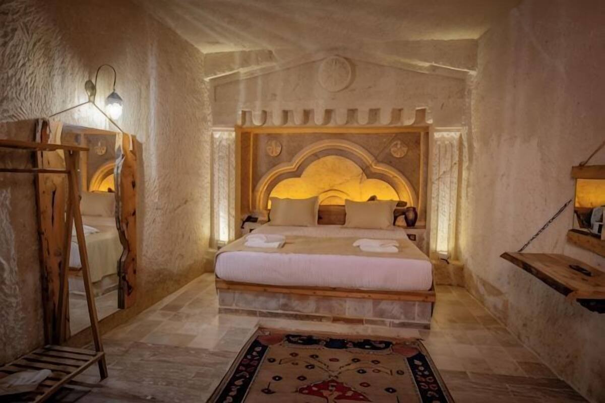 Une chambre à coucher avec un grand lit, une échelle en bois, une table de chevet et une lampe fixée au mur.