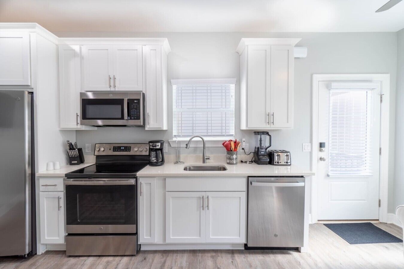 A modern kitchen with white cabinets, stainless steel appliances, and a black countertop.