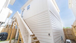 Un camper bianco con un patio in legno e una piccola finestra.