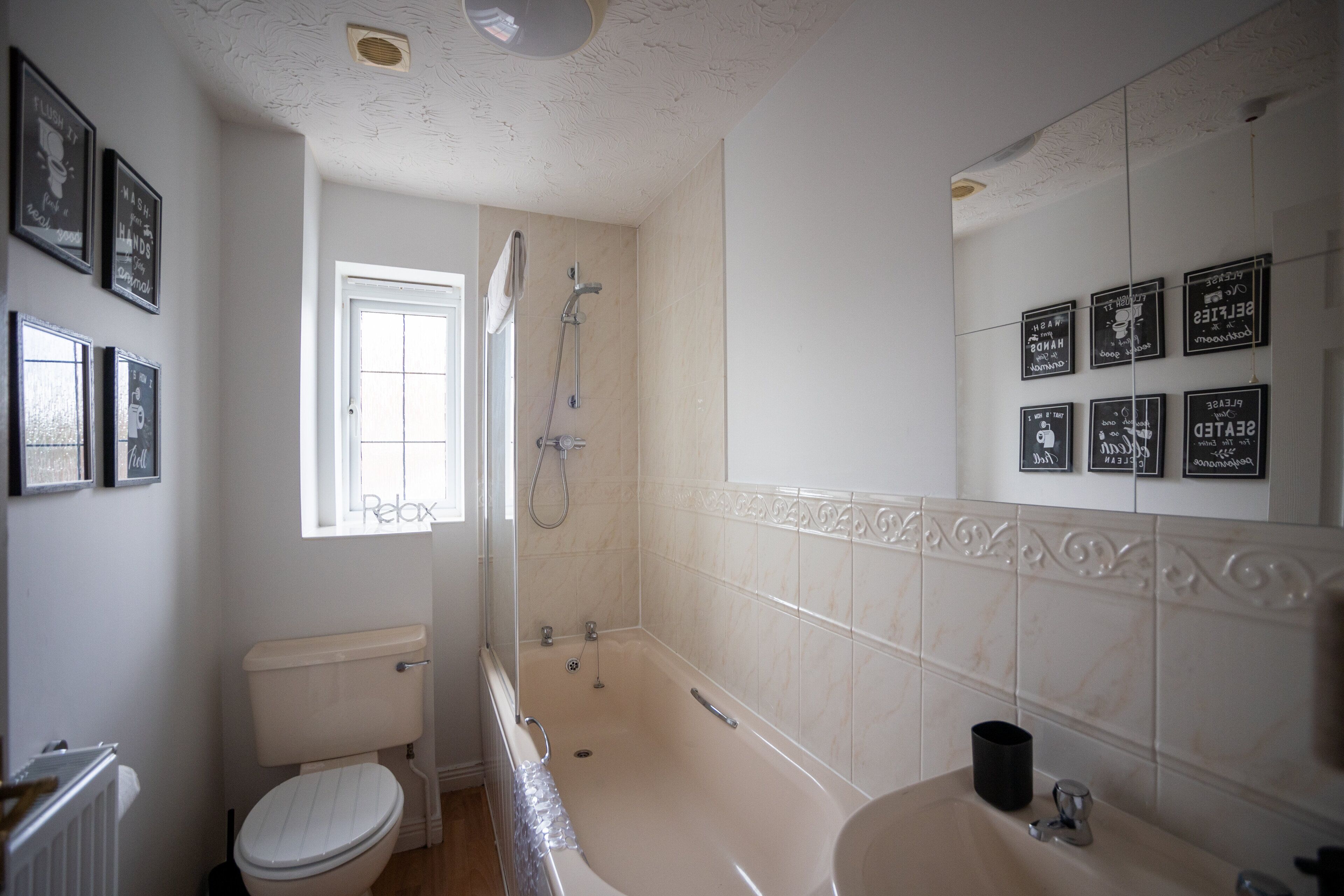 Un bagno con WC, vasca e lavandino. Alle pareti, alcune citazioni incorniciate.