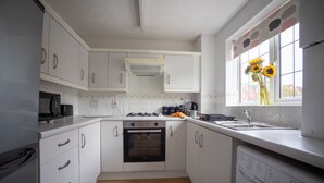 Een moderne keuken met witte kasten, een ingebouwde oven, een magnetron en een vaatwasser.