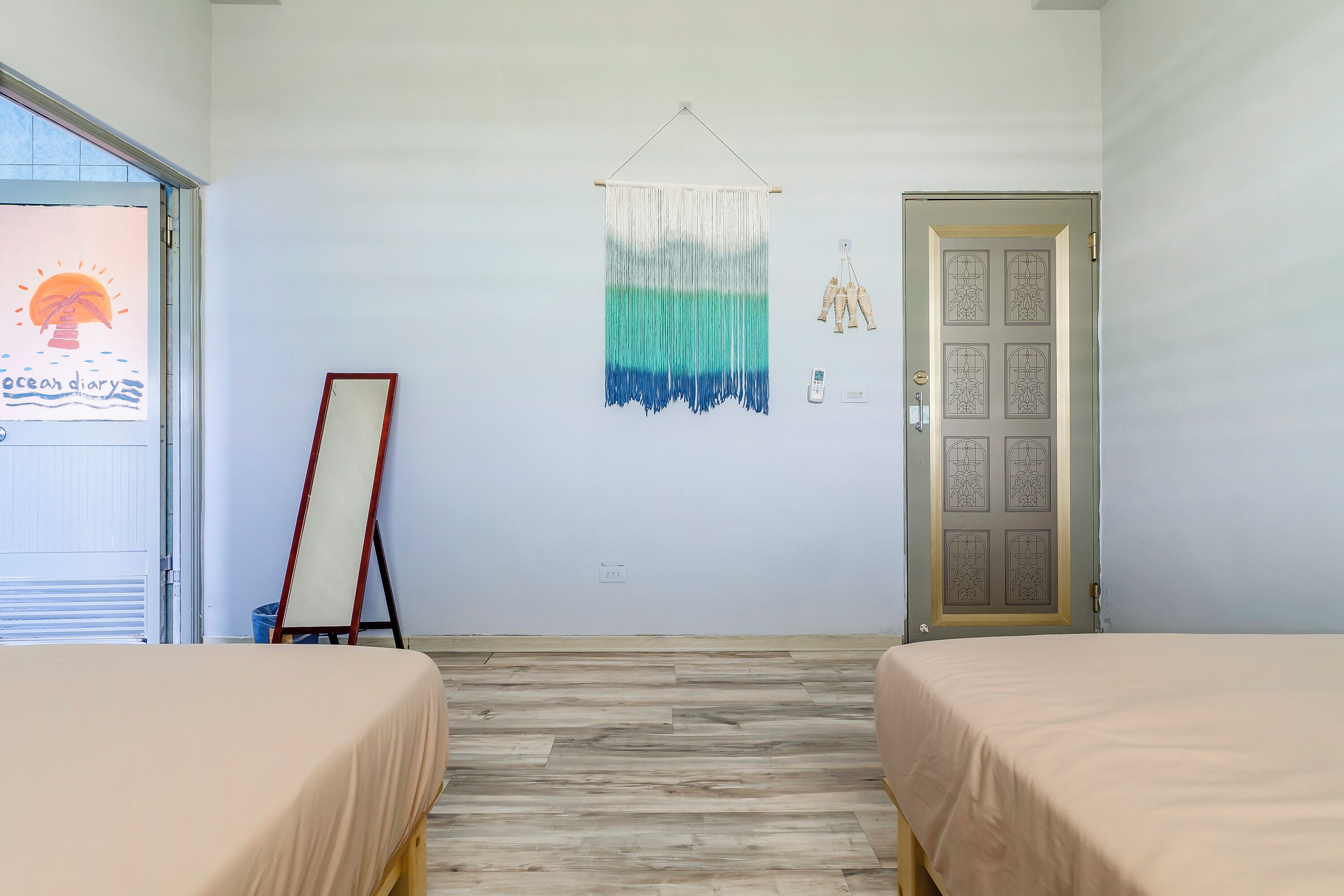 A room with two beds, a wall hanging, and a door with a decorative panel.