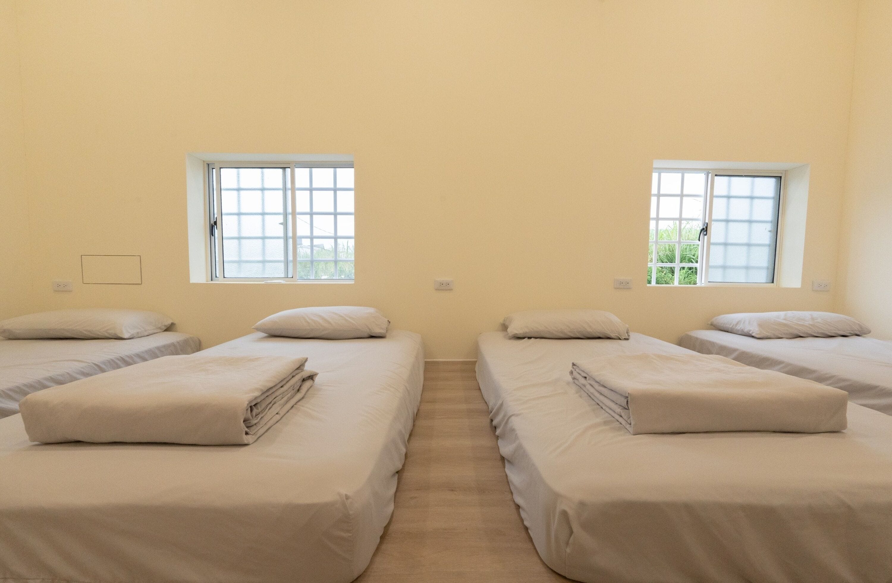 Quarto com duas camas, cada uma com janela e interruptor na parede.
