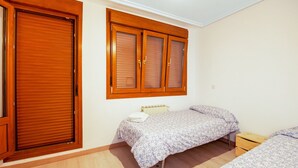Un dormitorio con dos camas individuales, un armario de madera y un radiador.