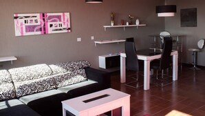 Una sala moderna con un sofá, una mesa de comedor con sillas y una zona de cocina.