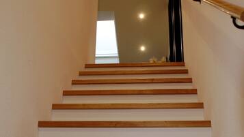 Eine Holztreppe mit Handlauf, die zu einem Zwischenpodest mit einem Fenster führt.