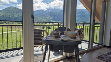 Ein Balkon mit Tisch für zwei Personen, mit Blick auf eine Berglandschaft.