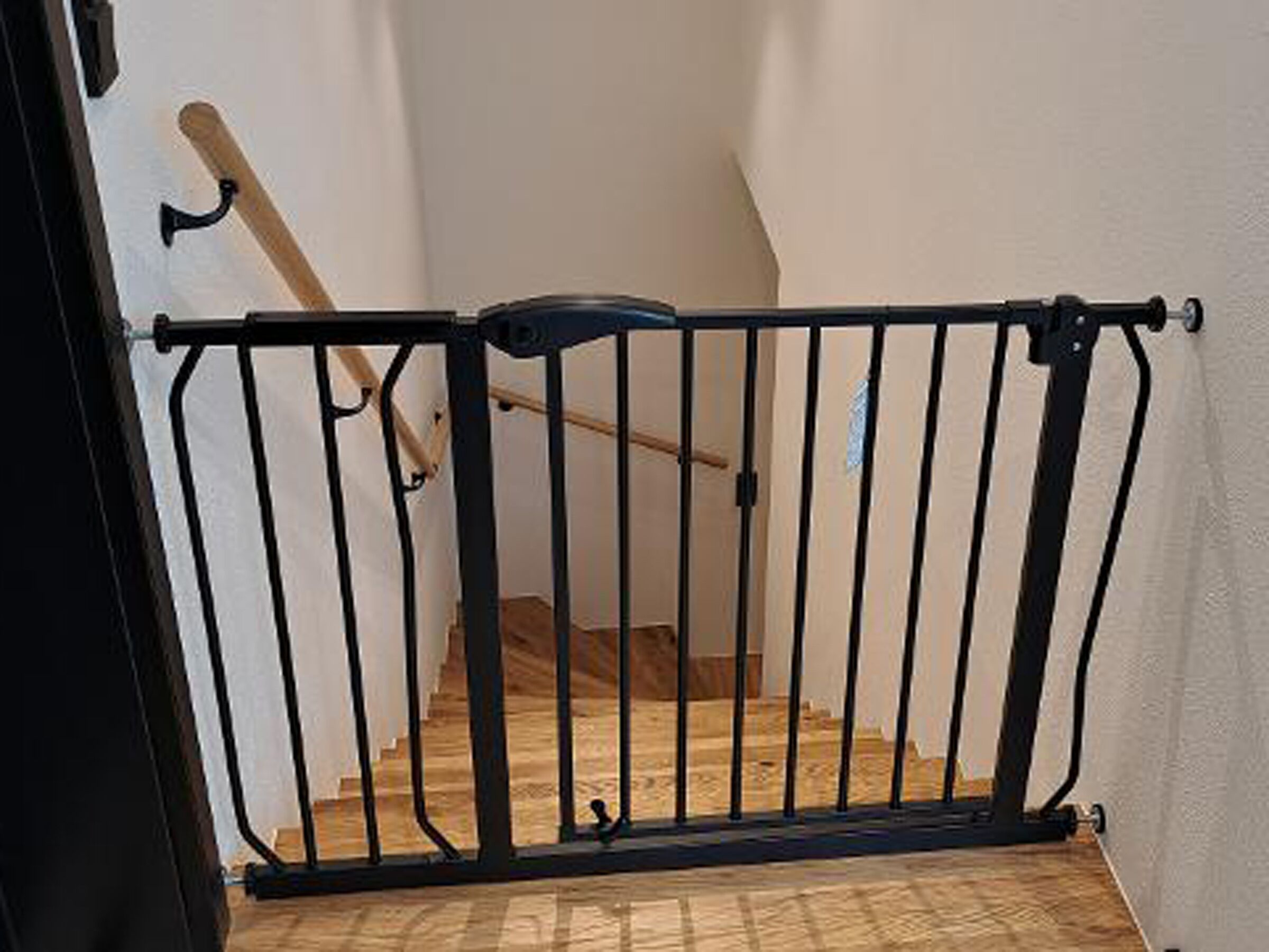 Um portão de metal preto dá acesso a uma escadaria de madeira.