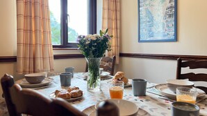 Una mesa de comedor dispuesta con platos, tazas y un florero con flores.