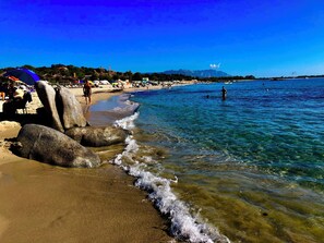 A beach with clear water, rocks, and people.