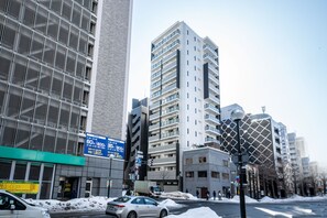 A modern urban street with high-rise buildings, a visible traffic light, and a snow-covered ground. - MOXIE 603 (Sapporo)