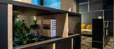 A modern interior with a bookshelf, a plant, and a framed picture.