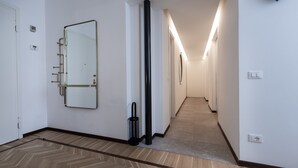 A hallway with a mirror, a trash bin, and a light fixture.