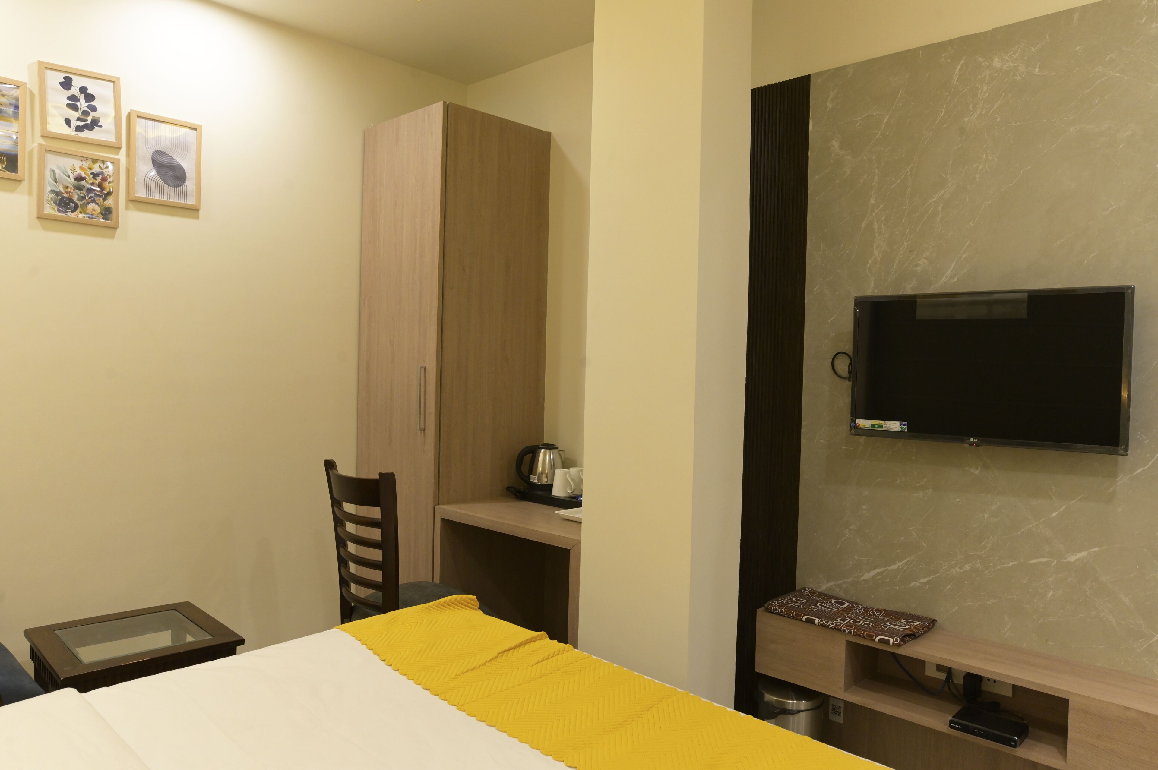 A hotel room with a bed, a desk, a television, and a wardrobe.