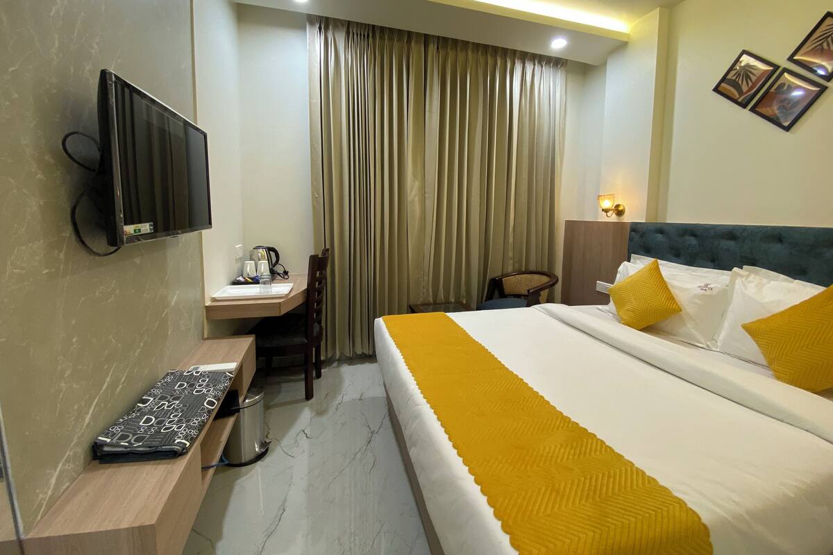 Ein Hotelzimmer mit Bett, Schreibtisch, Stuhl, Fernseher und Vorhang.