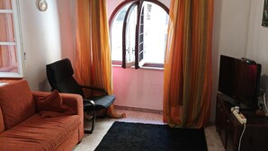A living room with a sofa, a chair, a black rug, a television, and curtains. - Vacation home in Tuscany park of Apuane near spa. Five Lands and Versilia (Monzone)