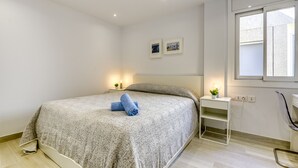A bedroom with a bed, bedside tables, a window, and a wall-mounted shelf. - DALLAS ATIC (Rosas / Roses)