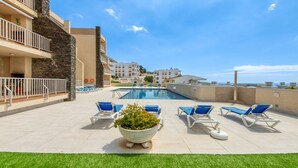 A rooftop pool area with blue lounge chairs and a large planter. - DALLAS ATIC (Rosas / Roses)