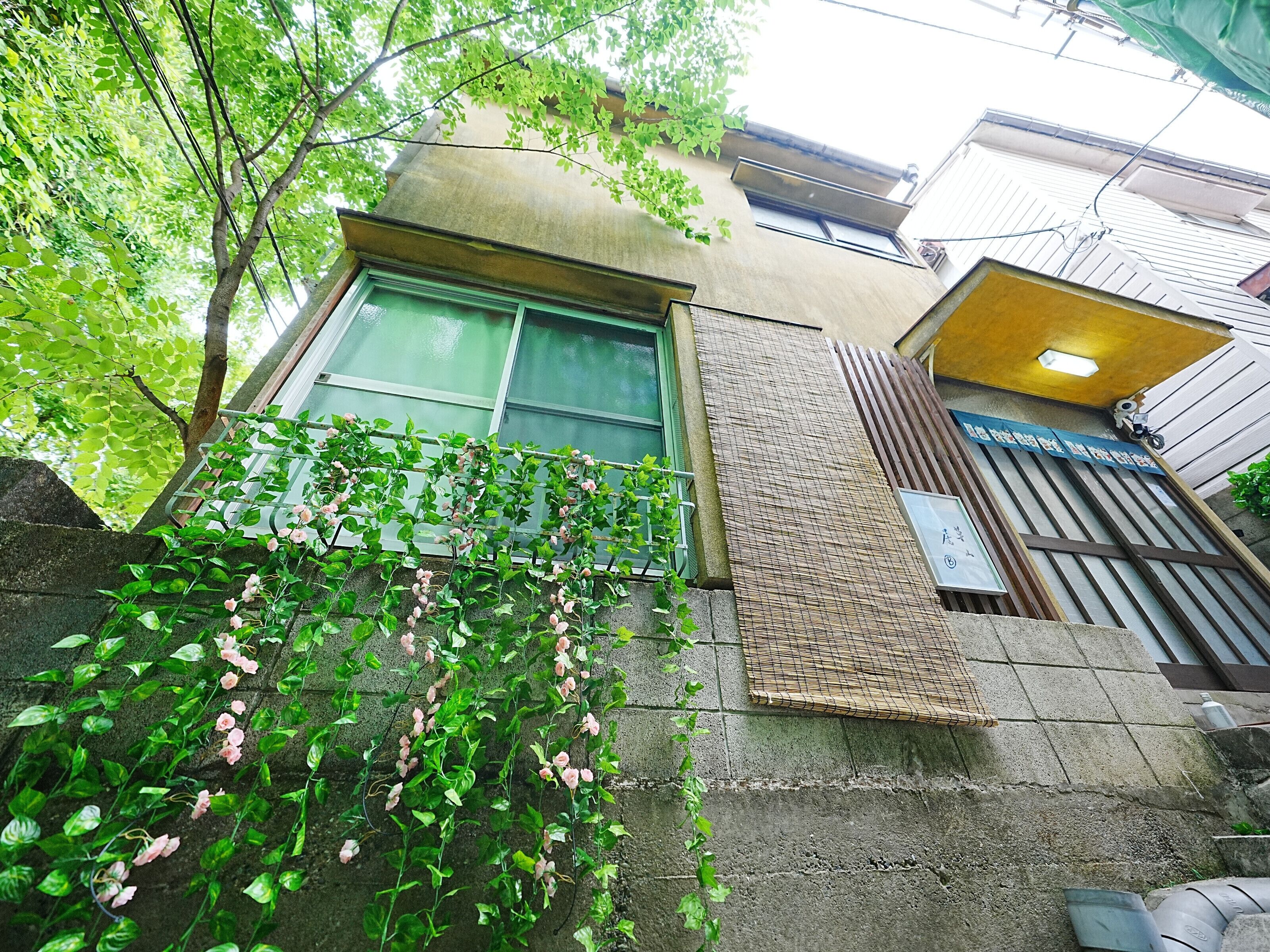 A building with a green window, a stone wall, and a metal fence.