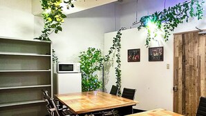 A conference room with a wooden table, black chairs, a whiteboard, and green plants.