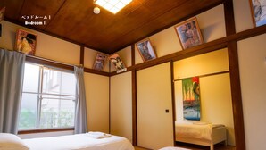 A traditional Japanese-style bedroom with two beds, a sliding door, and artwork on the walls.