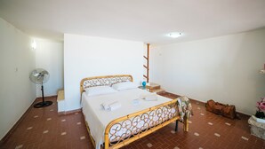 A bedroom with a bed, a standing fan, a suitcase, and a nightstand. - Casa Panorama Front of the Sea (Melendugno)