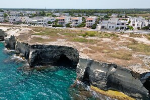 A coastal town with white buildings, a rocky cliff, and clear turquoise sea. - Casa Panorama Front of the Sea (Melendugno)