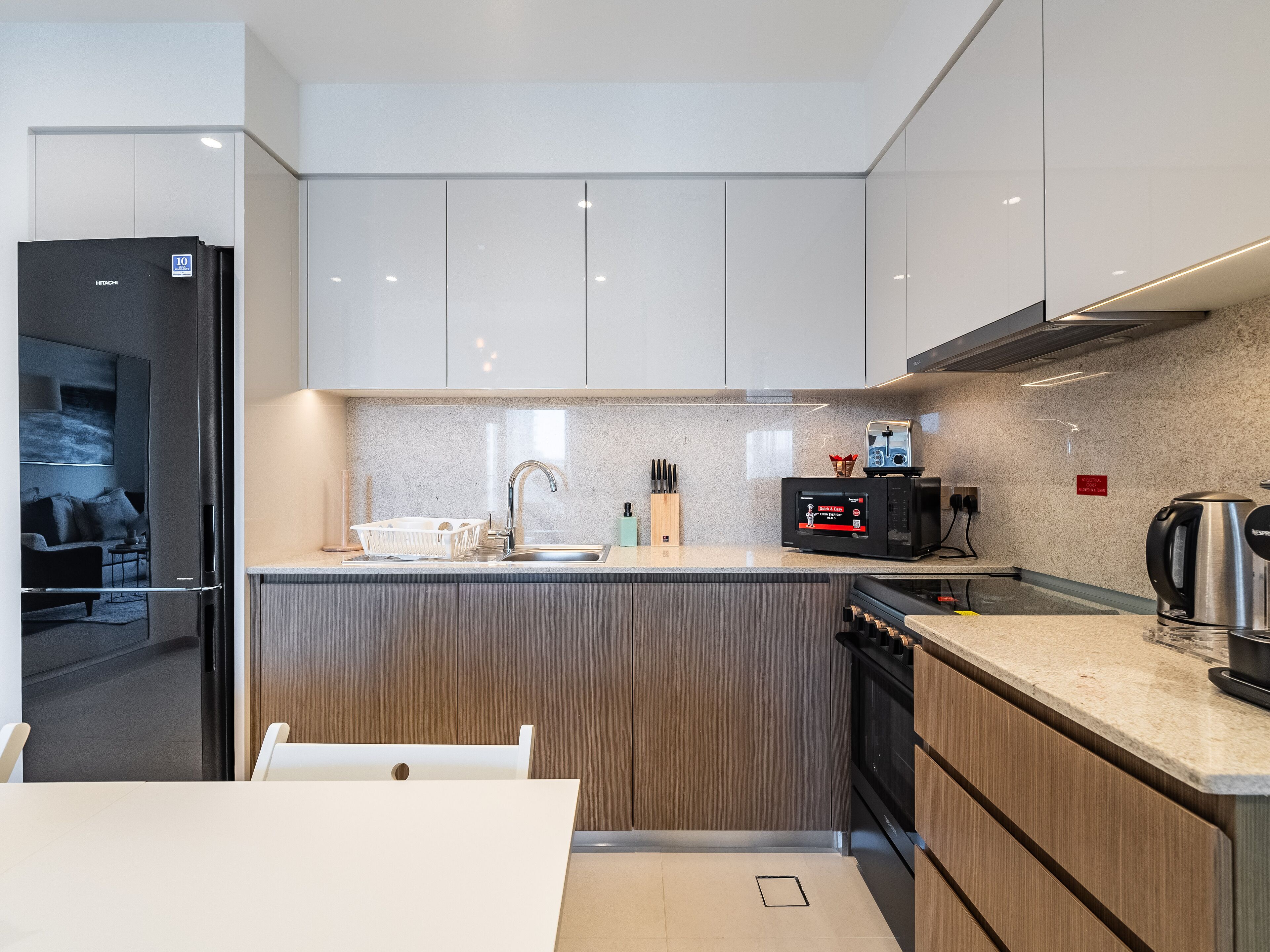 A modern kitchen with a built-in dishwasher, a stainless steel kettle, and a microwave.