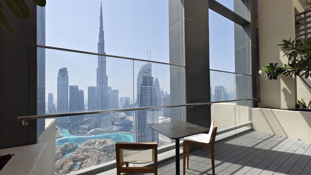 A balcony with a view of a city skyline, including a prominent skyscraper. - Cityscape Splendor Lavish 1BR Uptown  (Dubai)