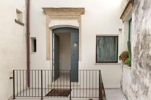A narrow courtyard with a metal railing, a door leading to a room, and a window with a cactus on the balcony. - 3778 Bastioni Luxury Home by Barbarhouse (Otranto)